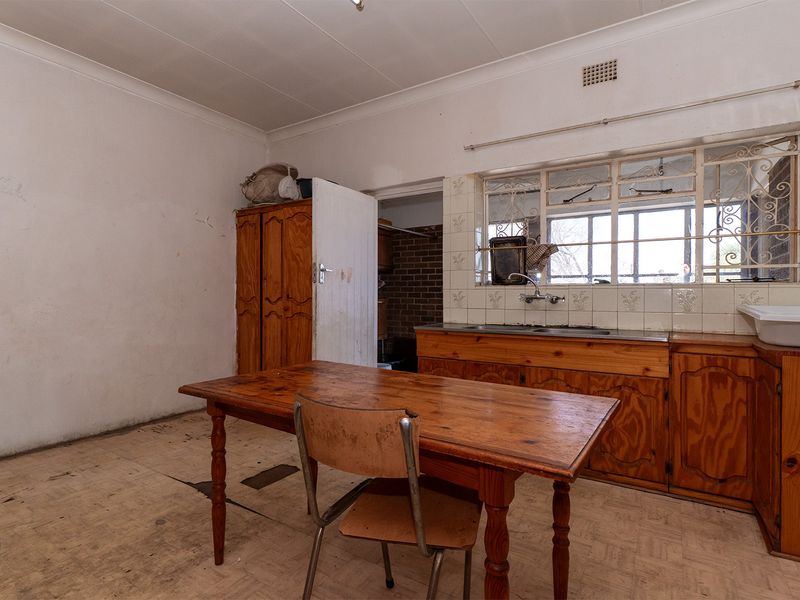 A dated kitchen featuring original wooden cabinetry, a stainless steel sink, and tiled splashbacks, offering significant potential for a modern renovation.