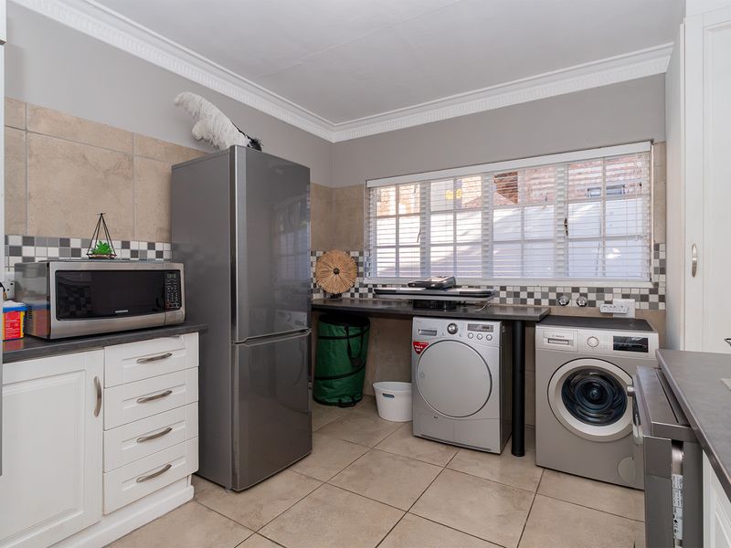 Functional laundry room featuring built-in cabinetry, tiled splashbacks, durable tiled flooring, and dedicated space for laundry appliances.