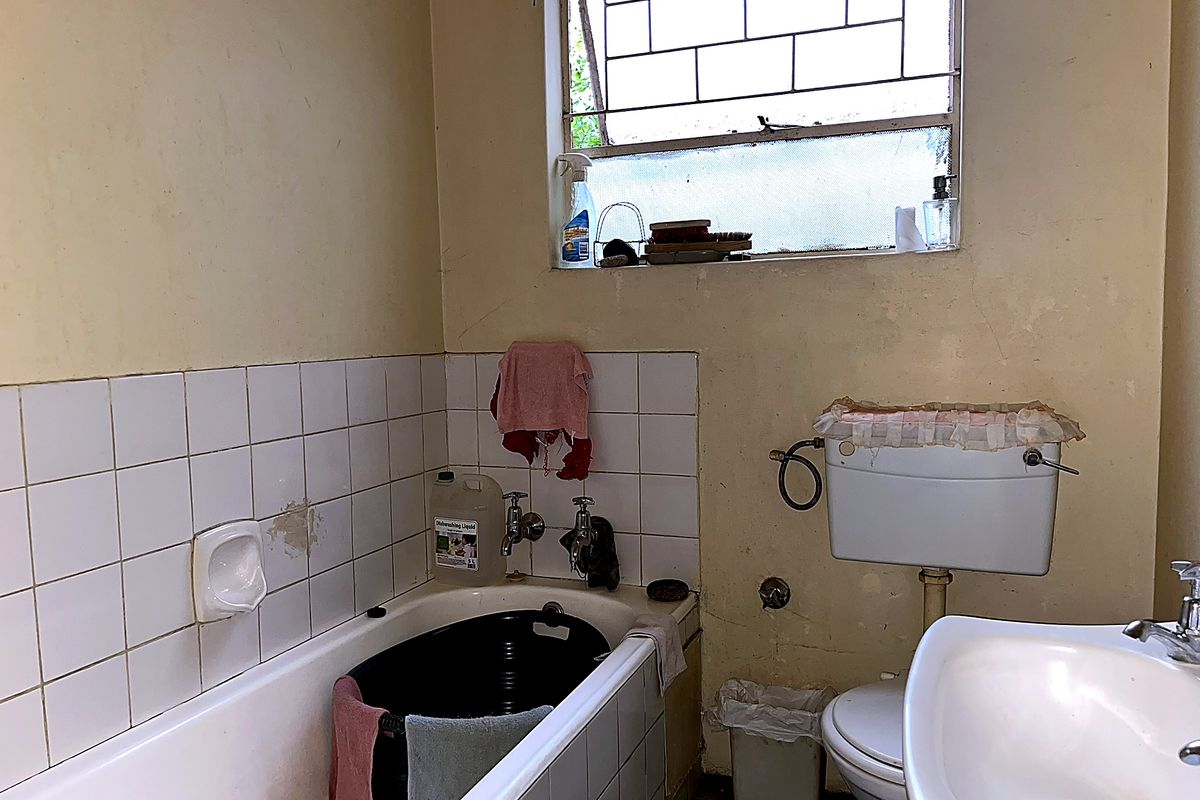 A dated bathroom featuring a bathtub, pedestal basin, and toilet, requiring significant cosmetic updates and repairs to wall finishes and fixtures.
