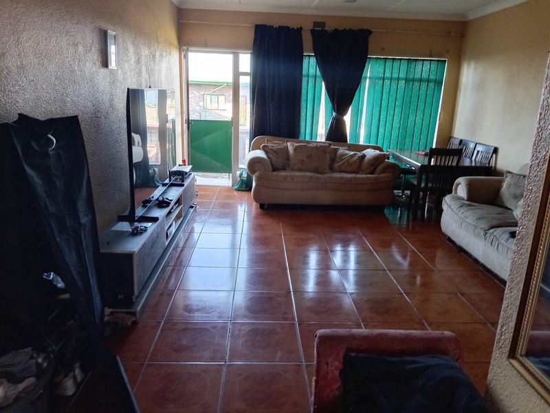 A living room featuring tiled flooring, a sliding glass door leading to an outdoor area, and vertical blinds.