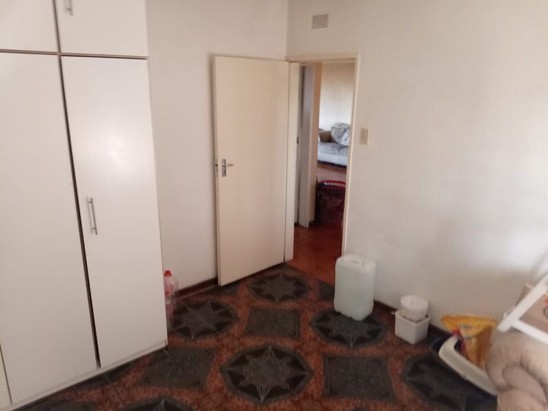 A bedroom featuring built-in cupboards and patterned floor tiles, offering a functional space ready for updates.