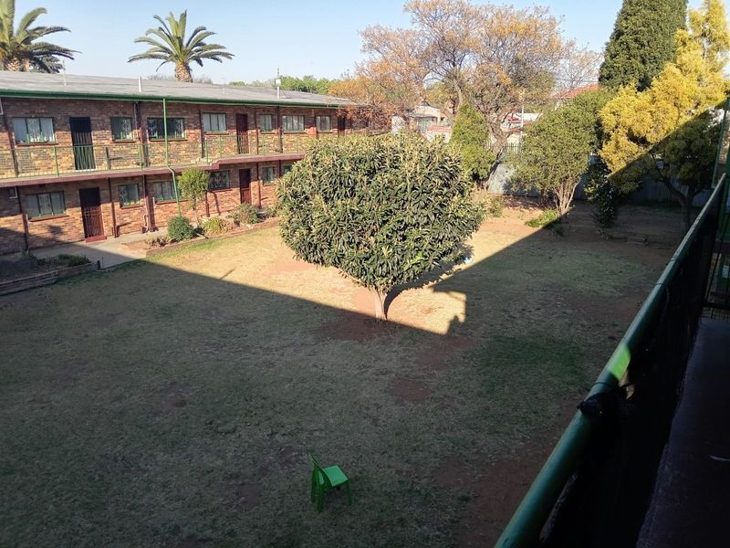 View of the communal garden and rear brick facade of the apartment complex from an elevated balcony.