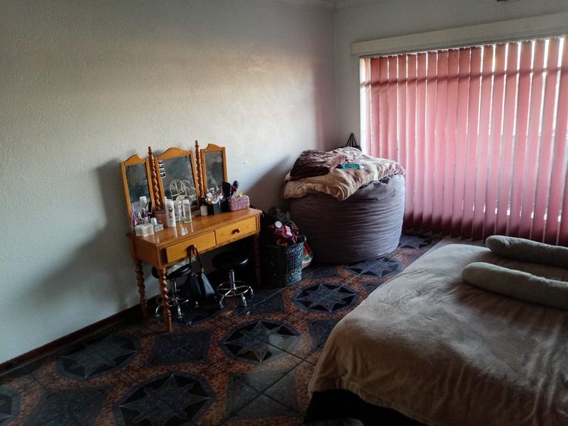 A bedroom featuring tiled flooring and vertical window blinds, offering a functional space ready for personalization.