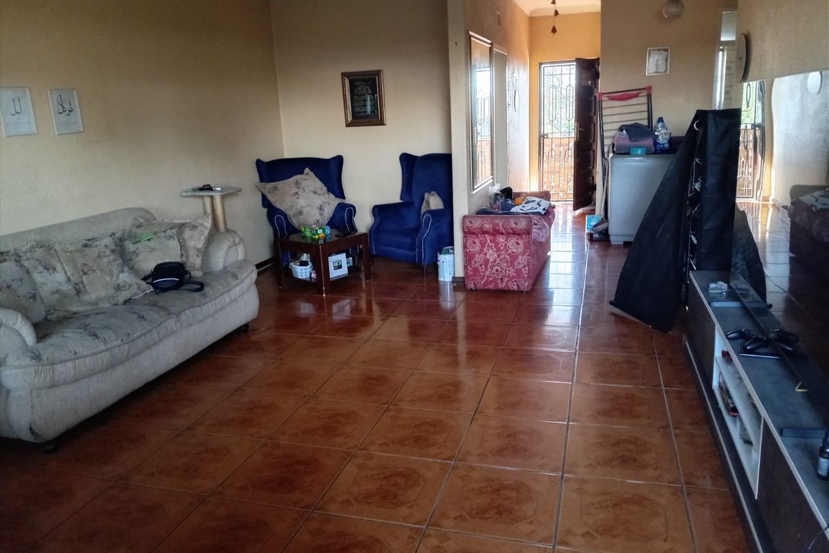 Spacious living area featuring ceramic floor tiles and a security gate entrance, offering a functional layout with neutral wall finishes.