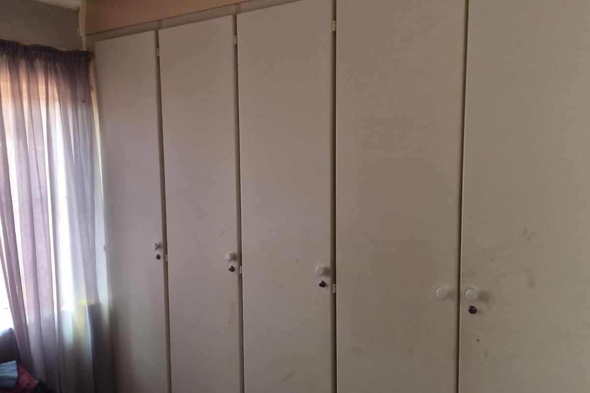 A bedroom featuring a wall of built-in cupboards with white doors, providing ample storage space.