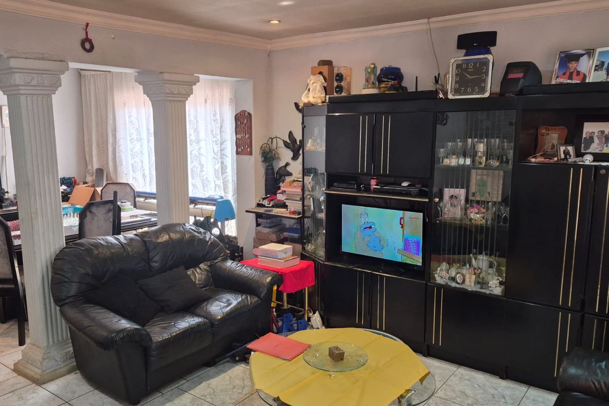 A living room area featuring decorative columns, tiled flooring, and recessed ceiling lighting, providing a functional space with potential for modern updates.