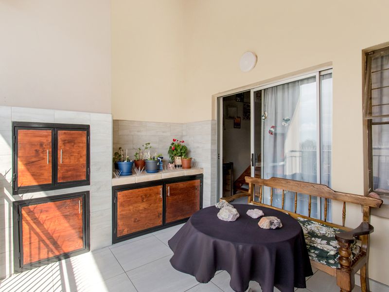 Covered balcony featuring a built-in braai, tiled surfaces, and direct access to the interior living space via sliding glass doors.