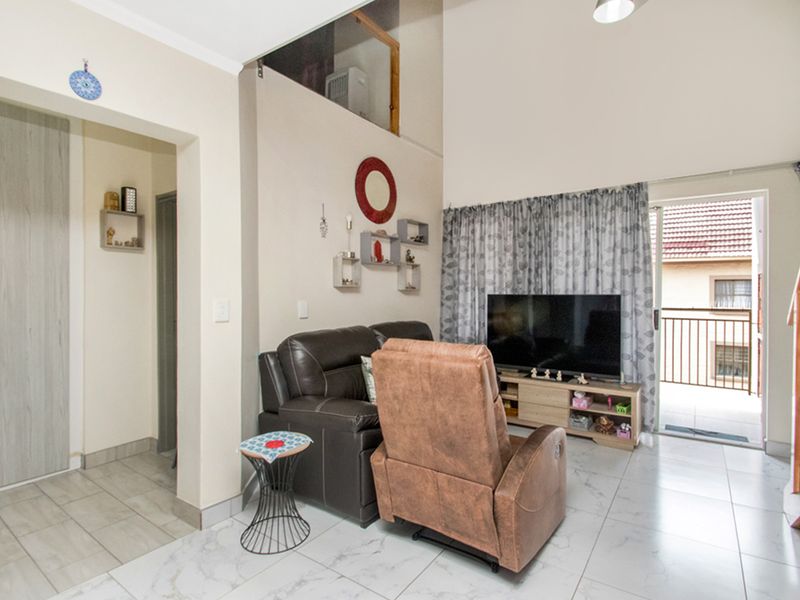 A bright living room featuring high ceilings, tiled flooring, and direct access to a private balcony, creating an airy and open atmosphere.