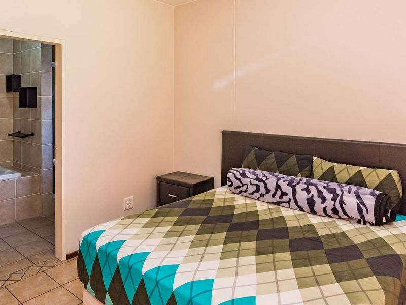 A bedroom featuring tiled flooring and an adjoining en-suite bathroom with a bathtub.