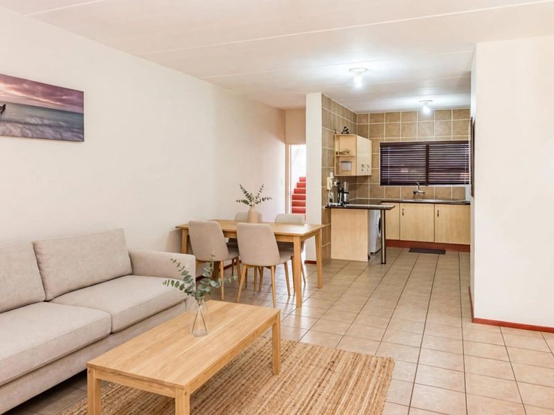 Open-plan living and dining area featuring tiled flooring and a functional kitchen with built-in cabinetry and tiled backsplash.