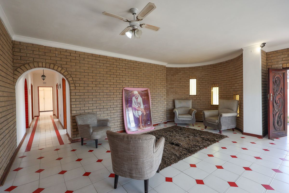 Spacious living area featuring distinctive exposed brick walls, tiled flooring with decorative accents, and an arched entryway leading to the hallway.