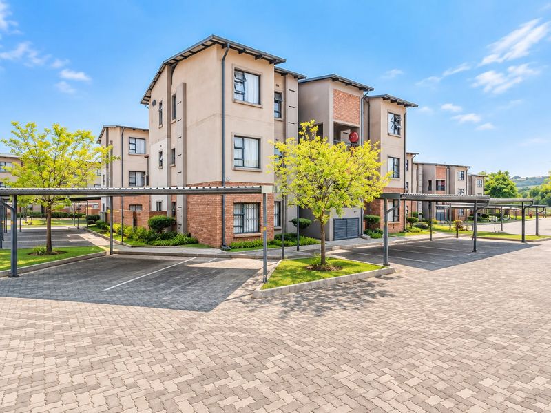 Exterior view of a modern apartment complex featuring paved parking areas, covered carports, and well-maintained brick and plaster facade architecture.