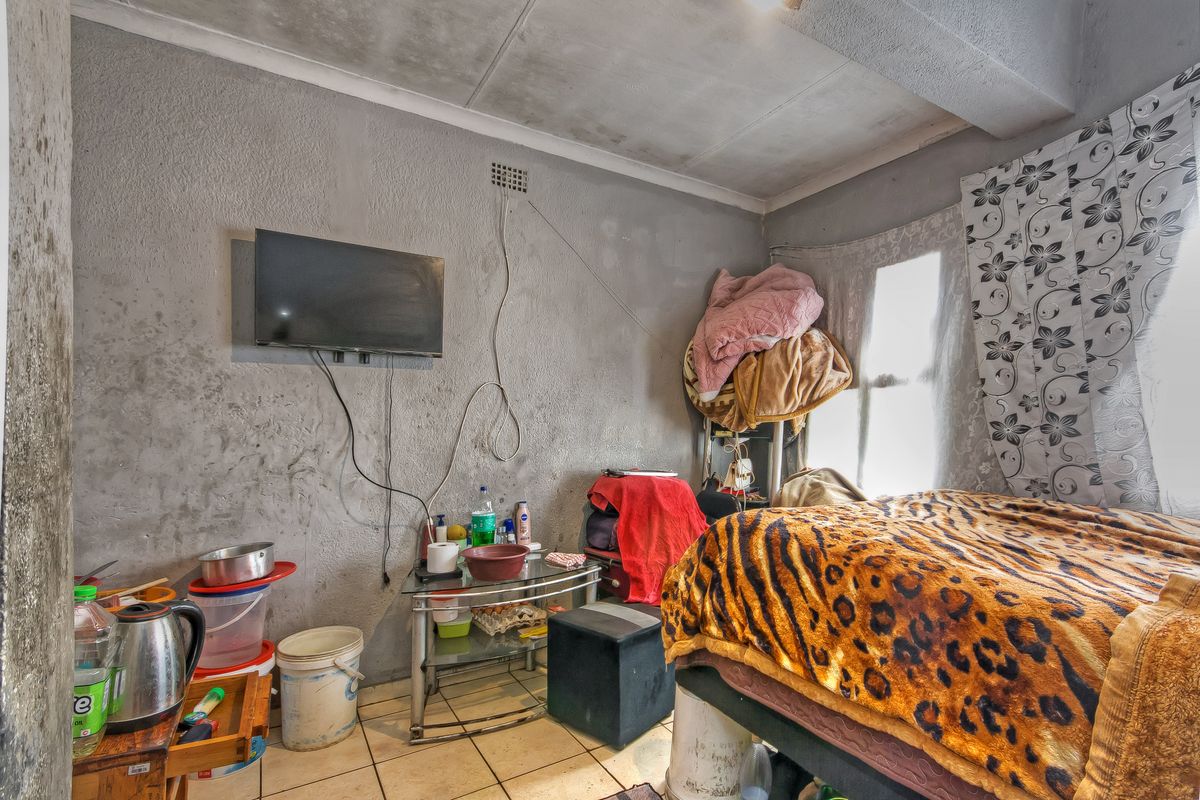 A bedroom featuring tiled flooring and a ventilation grille, requiring cosmetic updates to the walls and ceiling to improve the overall finish.