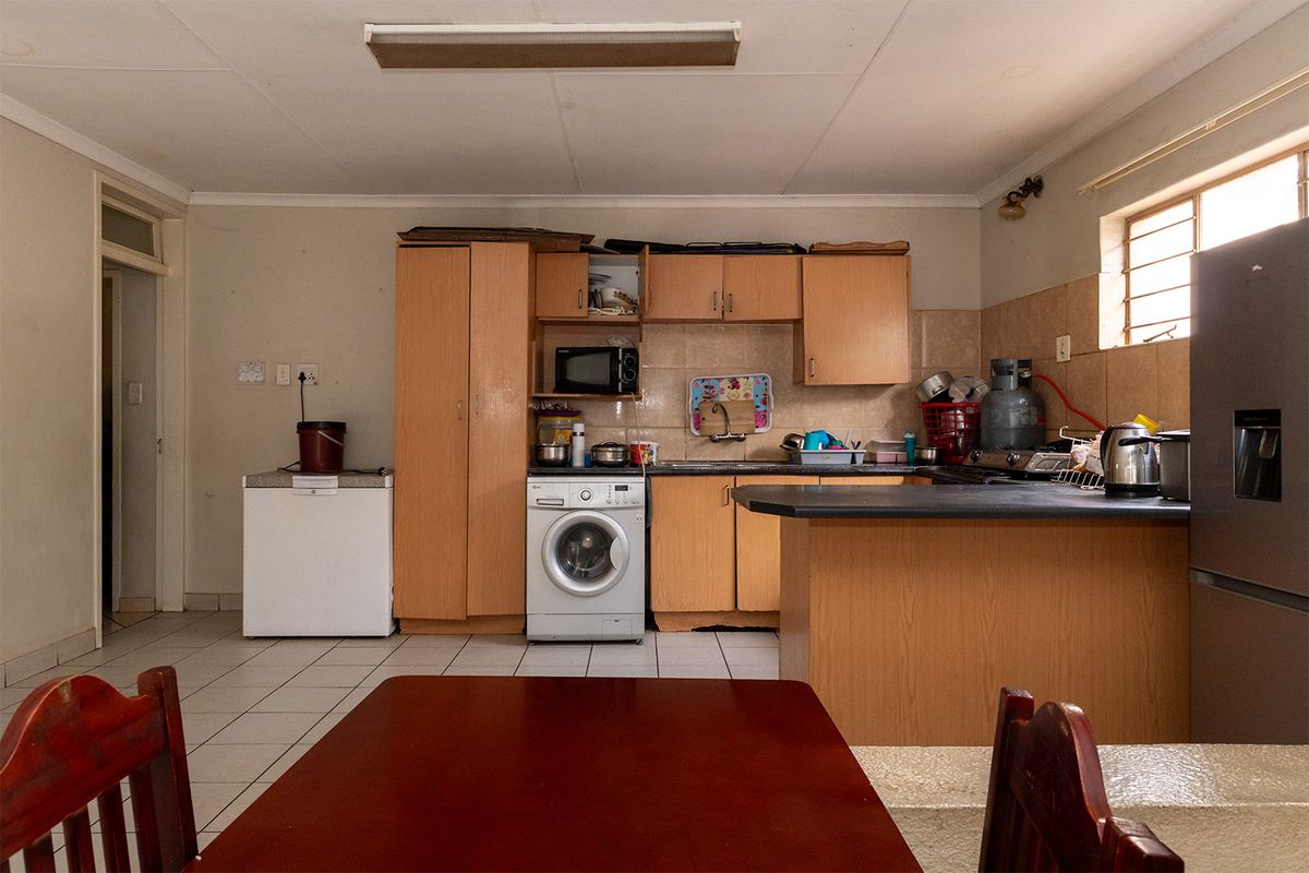 A functional kitchen featuring built-in wooden cabinetry, tiled backsplash, and a breakfast bar, offering a practical layout with tiled flooring throughout.