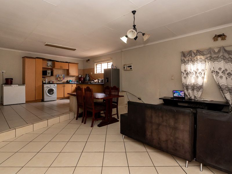 Open-plan living and kitchen area featuring tiled flooring, a raised kitchen platform, and built-in cabinetry, offering a functional layout for daily living.