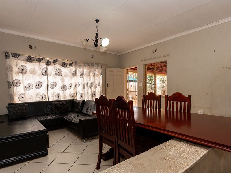 Open plan living and dining area featuring tiled flooring and a breakfast bar, providing a functional space for daily living and entertaining.