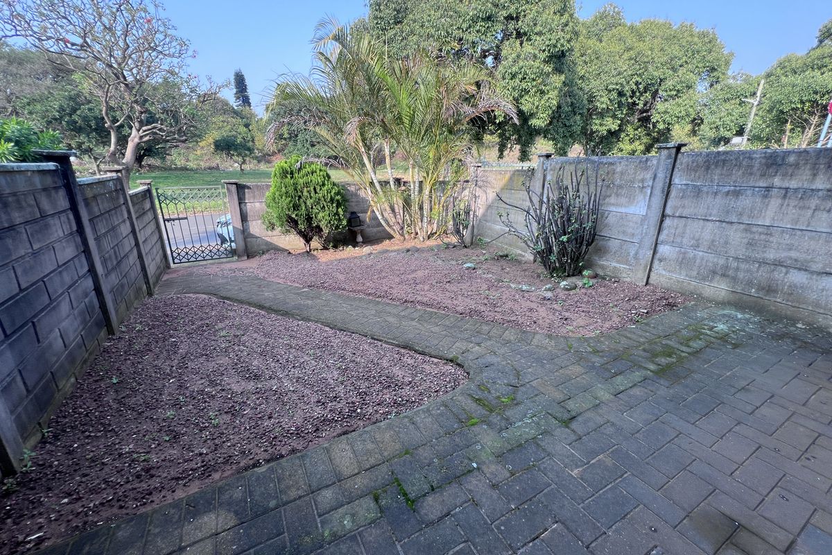 A private rear courtyard featuring a paved patio area, gravel garden beds, and secure perimeter walling with a pedestrian gate.