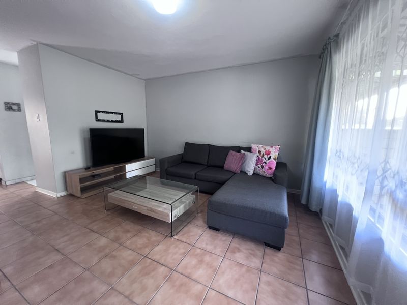A living room featuring ceramic tile flooring and neutral wall finishes, providing a functional space for relaxation.