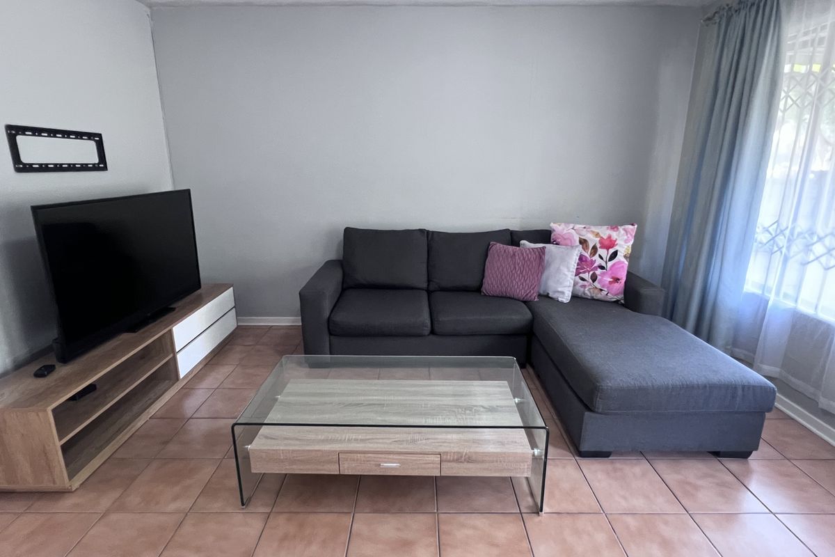 A living room featuring tiled flooring and neutral wall tones, providing a functional space with natural light from the window.