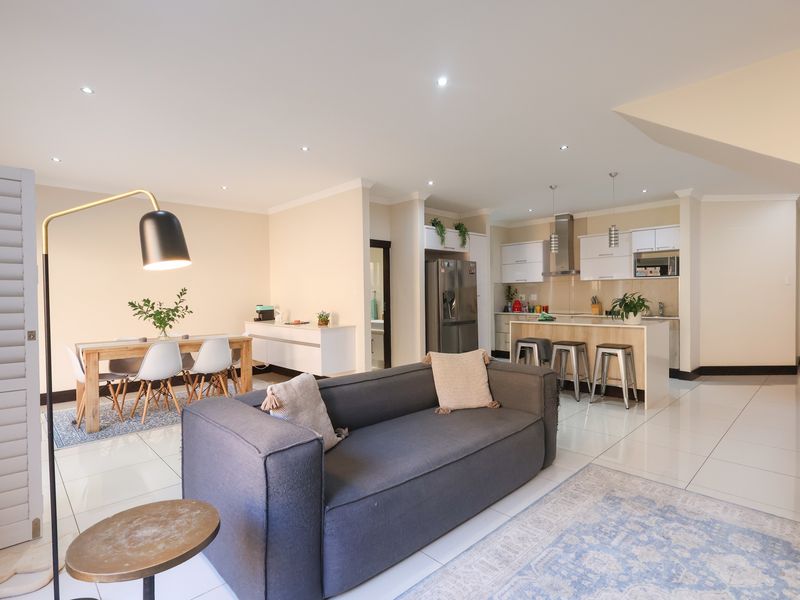 Spacious open-plan living area featuring a modern kitchen with an island, sleek cabinetry, and tiled flooring throughout, creating a bright and functional living space.