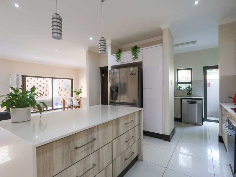 Modern open-plan kitchen featuring a central island with quartz countertops, sleek cabinetry, and seamless flow into the adjacent living and dining areas.