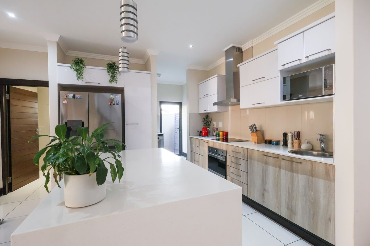 Modern kitchen featuring a central island, stone countertops, built-in appliances, and contemporary cabinetry with ample storage space.