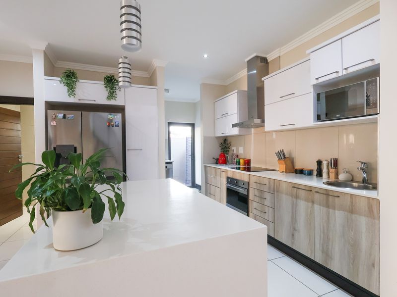 Modern kitchen featuring a central island, stone countertops, built-in appliances, and contemporary cabinetry with ample storage space.