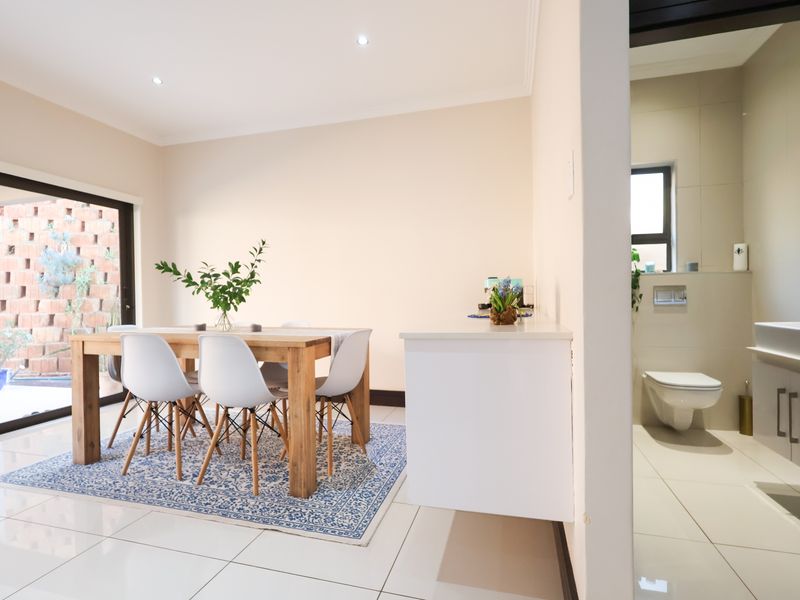 Open plan dining area featuring large sliding doors to a private courtyard, adjacent to a modern bathroom with wall-hung fixtures and sleek tiling.