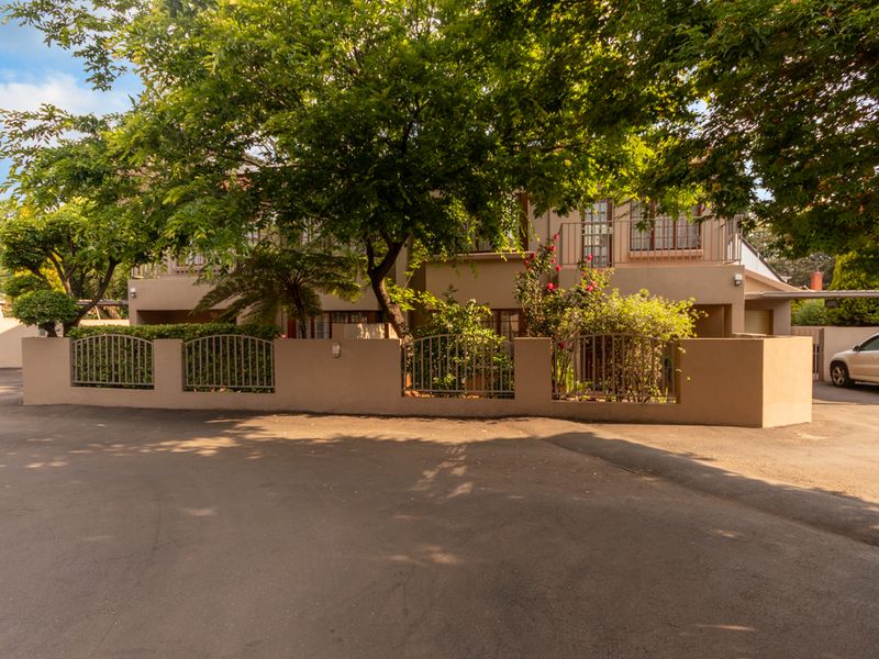Front view of the apartment complex featuring a secure boundary wall, metal fencing, and a paved driveway entrance.