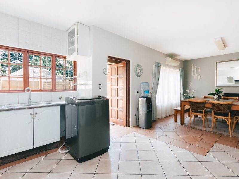Open-plan kitchen and dining area featuring tiled flooring, functional cabinetry, and direct access to an exterior door.