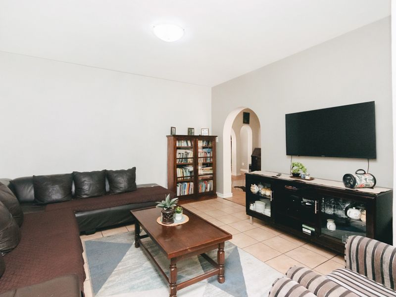 A comfortable living room featuring tiled flooring and a distinctive arched doorway leading to adjacent areas of the apartment.