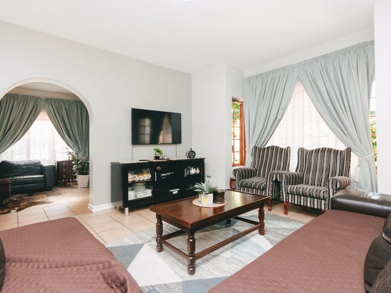 A comfortable living room featuring tiled flooring, coved cornicing, and an arched doorway leading to an adjacent space.