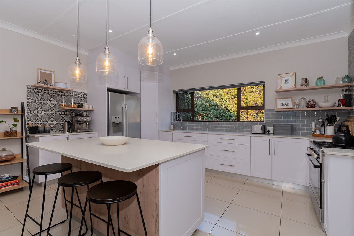 Modern kitchen featuring a central island with quartz countertops, white cabinetry, subway tile backsplash, and stylish pendant lighting with large window views.