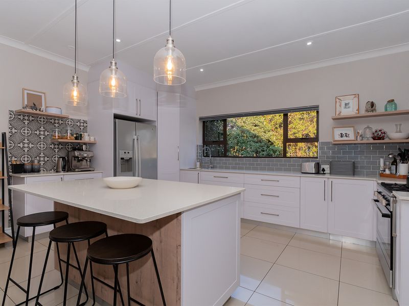 Modern kitchen featuring a central island with quartz countertops, white cabinetry, subway tile backsplash, and stylish pendant lighting with large window views.