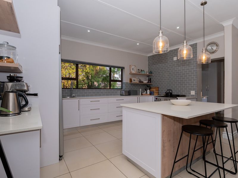Modern kitchen featuring a central island with breakfast bar, quartz countertops, subway tile backsplash, and contemporary pendant lighting.