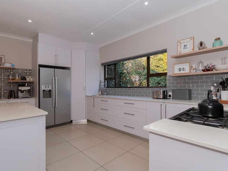 Modern kitchen featuring white cabinetry, stone countertops, a gas hob, subway tile backsplash, and a large window overlooking the garden.