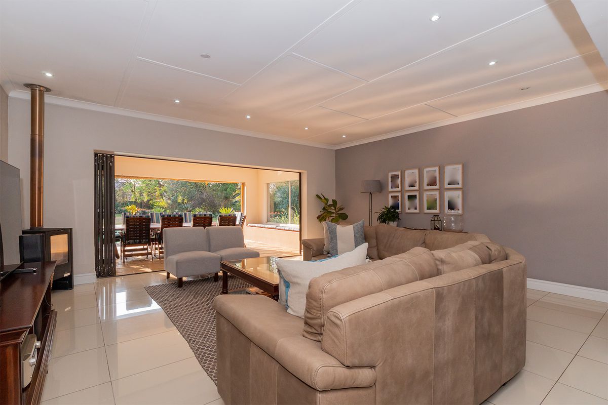 Spacious living room featuring polished tile flooring, a modern freestanding fireplace, and large stacking doors that open onto an outdoor patio area.