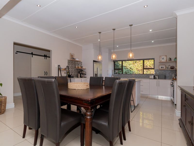 Spacious open-plan kitchen and dining area featuring modern cabinetry, a kitchen island, stylish tile backsplashes, and bright recessed lighting throughout.