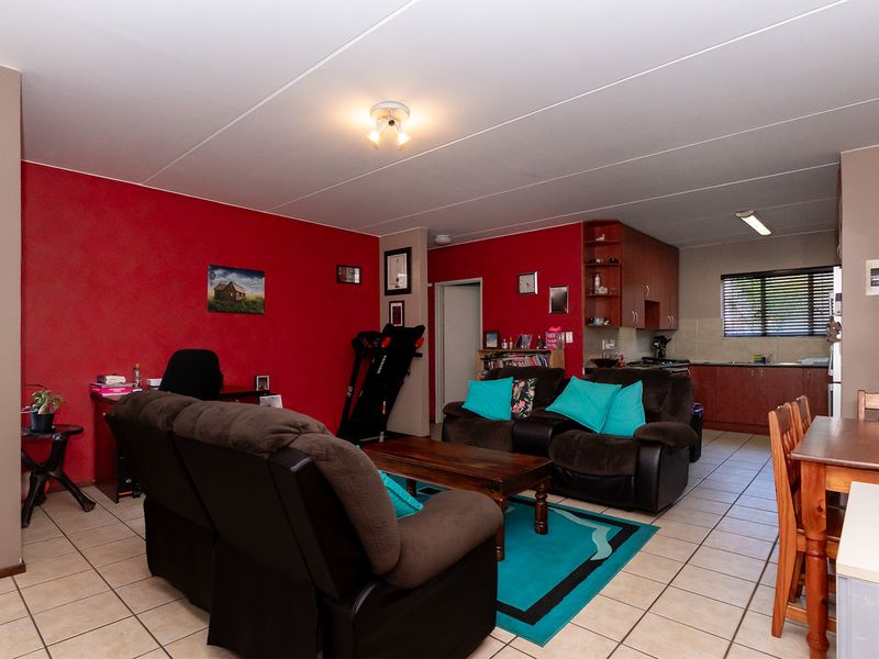 Open-plan living and kitchen area featuring tiled flooring and functional built-in cabinetry, offering a versatile space for dining and relaxation.