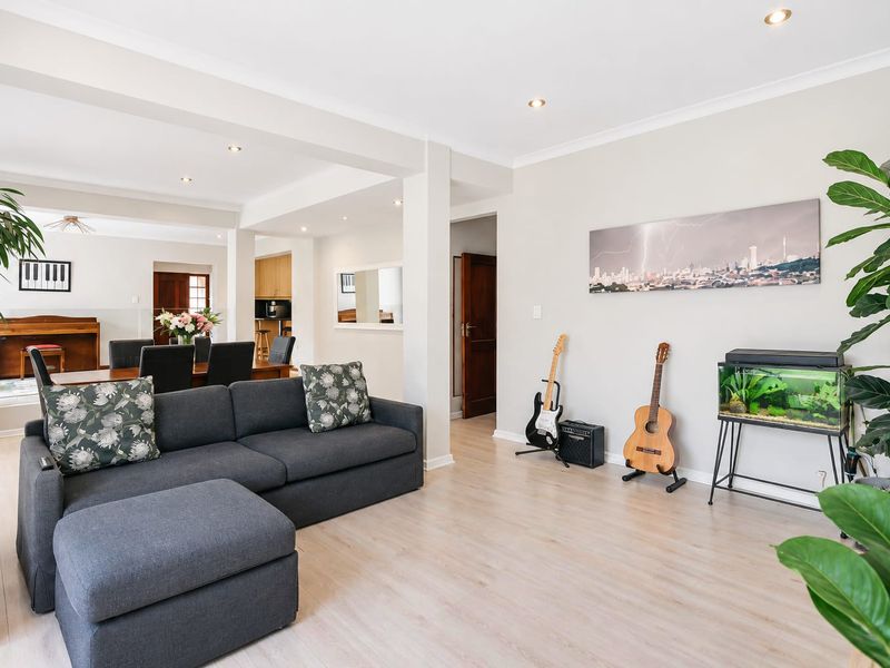 Spacious open-plan living and dining area featuring light laminate flooring, recessed downlighting, and a neutral color palette.