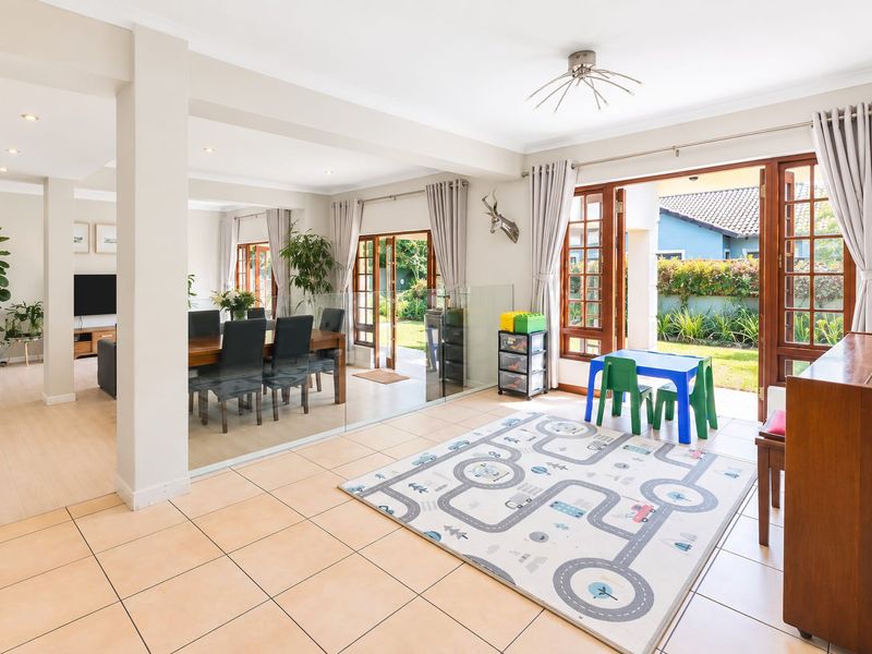 Spacious open-plan living and dining area featuring tiled flooring, recessed lighting, and large glass doors providing seamless access to the rear garden.