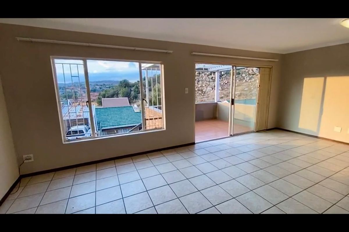 Spacious, light-filled living area featuring neutral tiled flooring and large sliding glass doors that open onto an outdoor patio with scenic views.