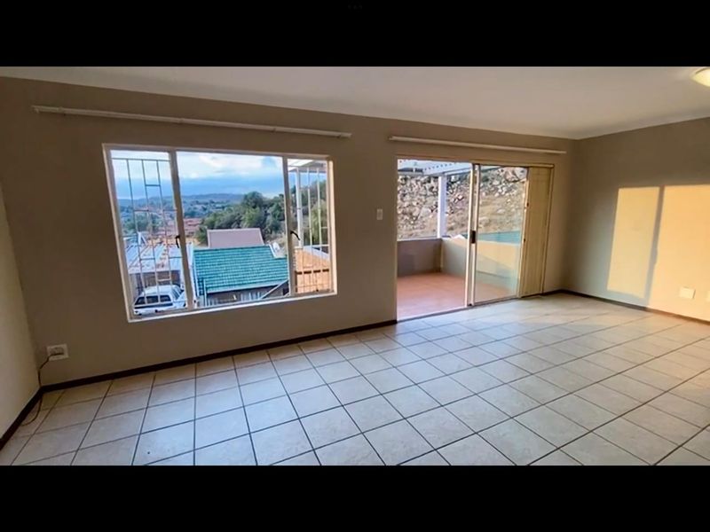 Spacious, light-filled living area featuring neutral tiled flooring and large sliding glass doors that open onto an outdoor patio with scenic views.