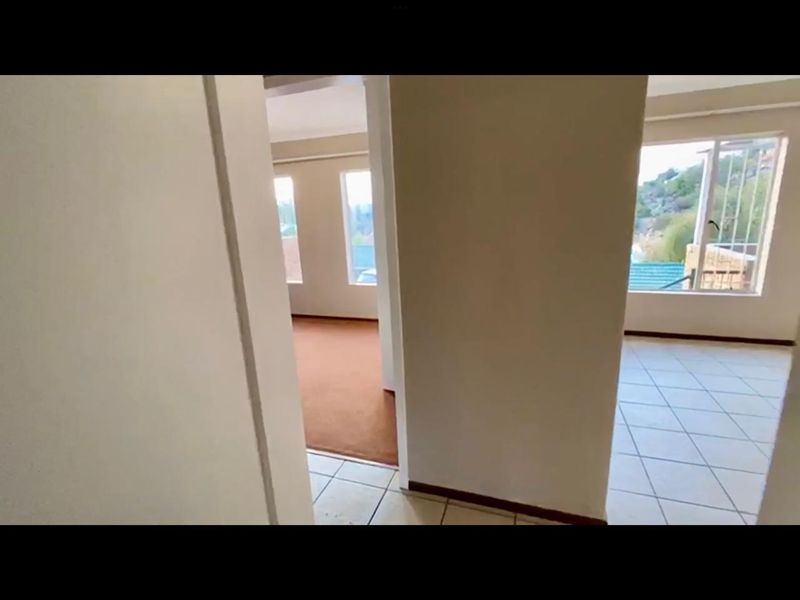 A view from a hallway looking into adjacent rooms featuring tiled and carpeted flooring with natural light from multiple windows.