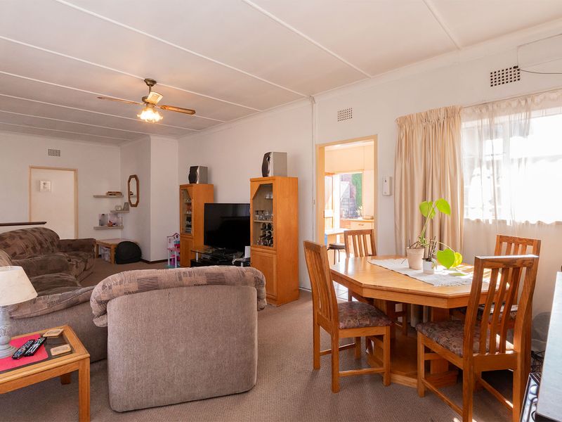 Open plan living and dining area featuring carpeted flooring, ceiling fan, and access to adjacent rooms.