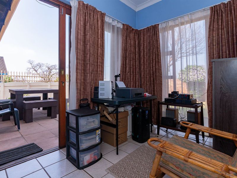 A sunroom or enclosed patio area featuring tiled flooring and large sliding glass doors providing direct access to the outdoor paved entertainment space.