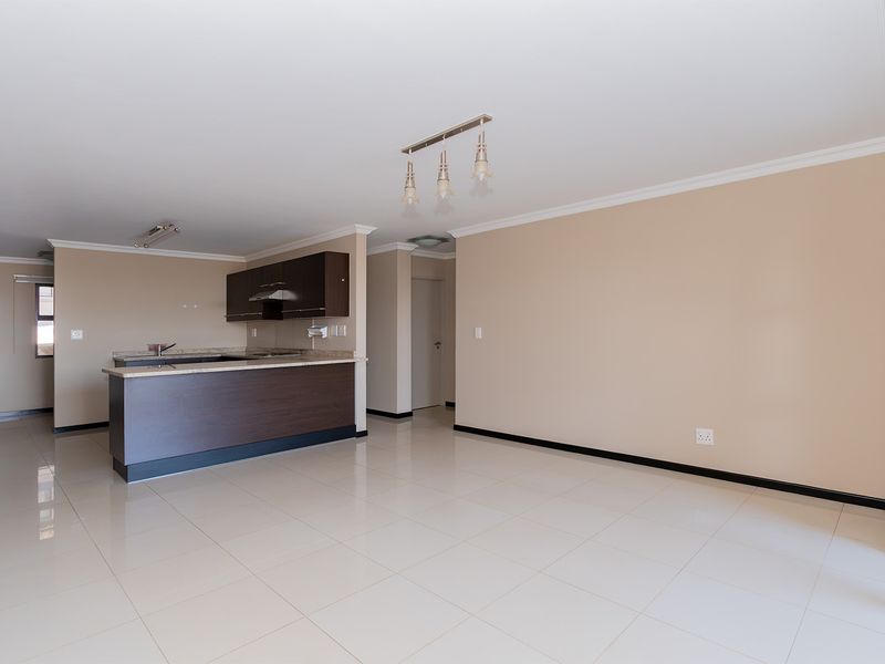 Spacious open-plan living area featuring tiled flooring, coved cornicing, and a modern kitchen with built-in cabinetry and granite countertops.
