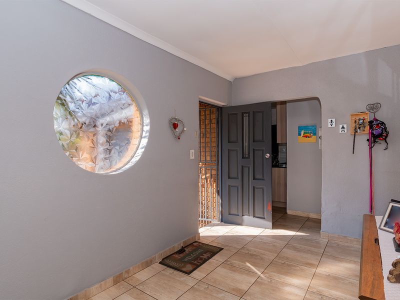 Entrance hall featuring tiled flooring, a distinctive circular window, and a secure panelled front door leading into the home.