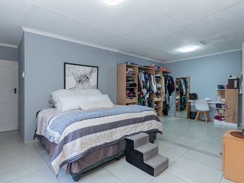 Spacious bedroom featuring tiled flooring, built-in cupboards, and neutral wall tones, offering a functional layout with ample storage space.