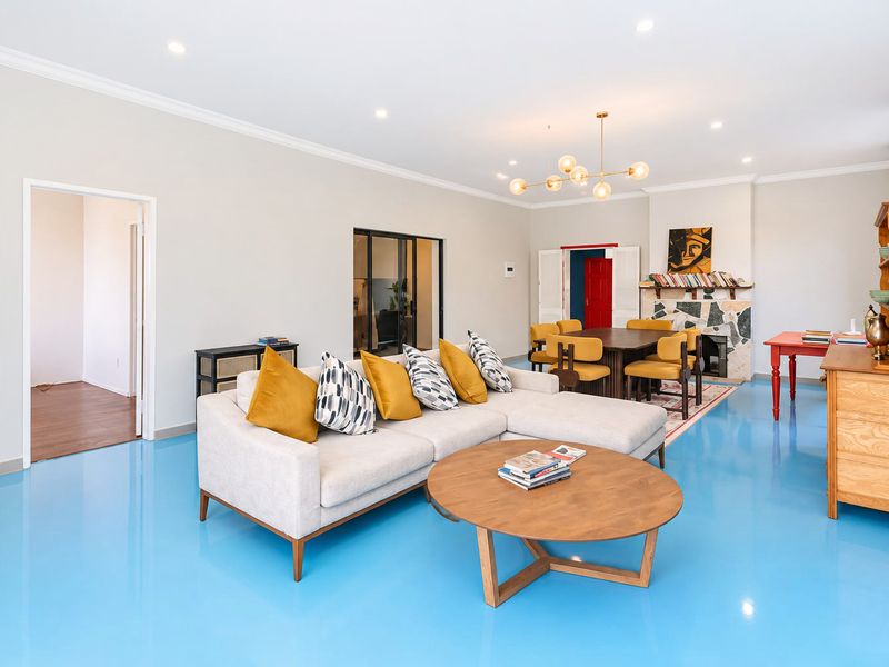 Spacious open-plan living and dining area featuring a stone fireplace, recessed lighting, and high-gloss blue epoxy flooring.